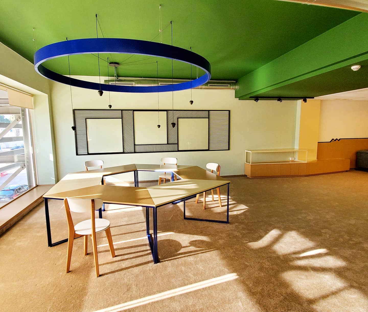 Espace de travail collaboratif avec plafond vert et tables hexagonales